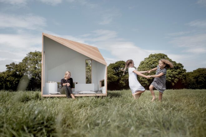 kids running in field outside small cabin playhouse
