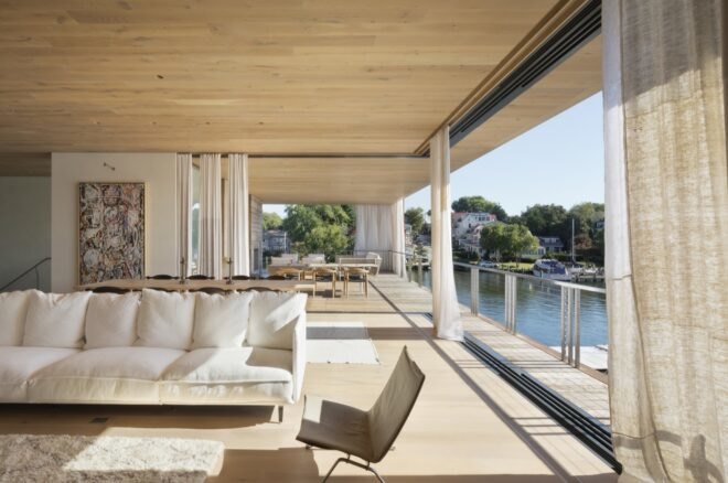large windows let in sunlight into the interior home with wooden floors