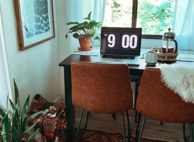 a small desk with two chairs and large computer screen