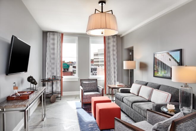 inside of a hotel room with large windows and white walls and light colored floors with gray couches