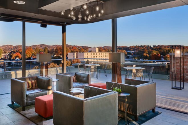 a roof top bar lounge area with gray couches offering mountainous views