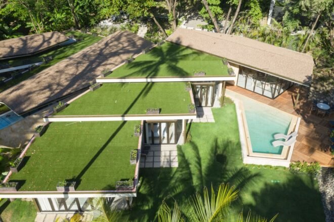 aerial view of home with green roof and a pool