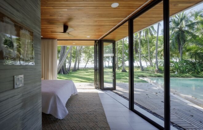 bedroom with large bed, wood ceilings and glass walls
