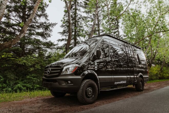 black van driving past trees