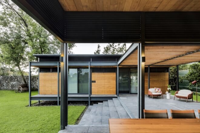prefabricated wood home in a u shape with stairs surrounded by grass and trees