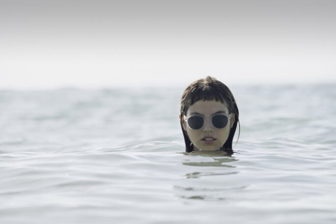 model in ocean wears clear framed sunlasses