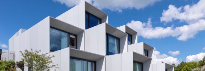 prefab housing in a white color with large windows nearby paved walkway and grass