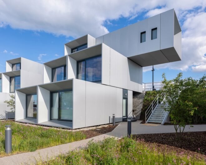 prefab housing in a white color with large windows nearby paved walkway and grass