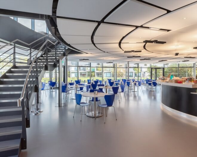 a large staircase and windows are seen in the interior of the structure's first floor