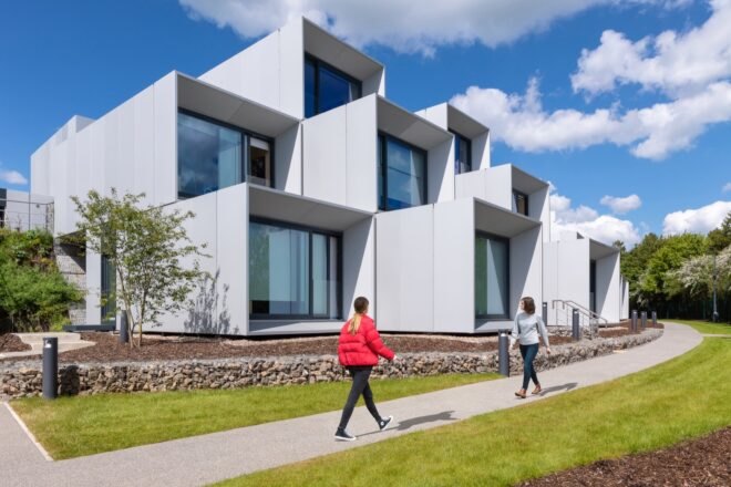 prefab housing in a white color with large windows nearby paved walkway and grass