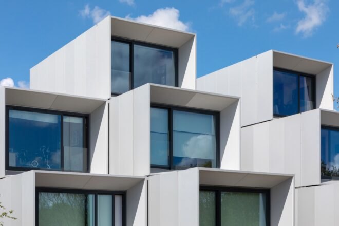 prefab housing in a white color with large windows nearby paved walkway and grass