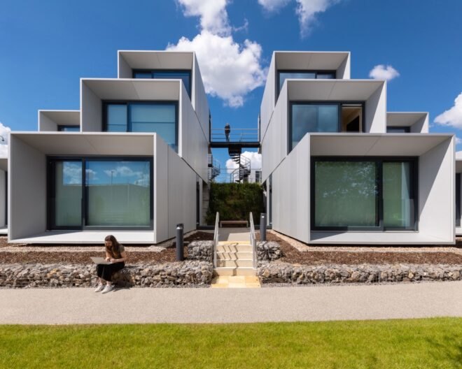 prefab housing in a white color with large windows nearby paved walkway and grass