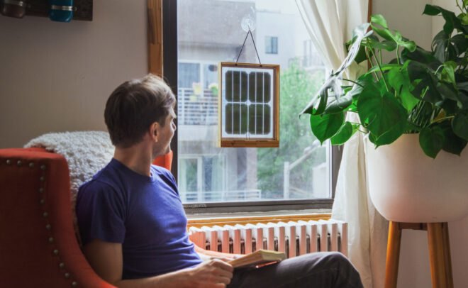 man sitting next to window with framed solar panels