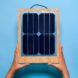 two hands holding a frame with solar panels