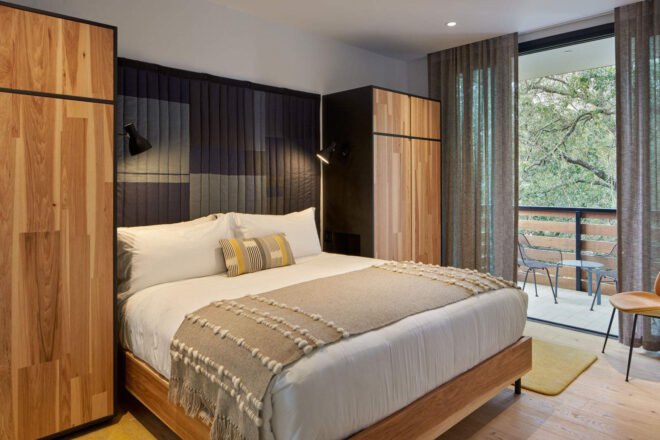 fluffy white bed in hotel room with black and wood accents