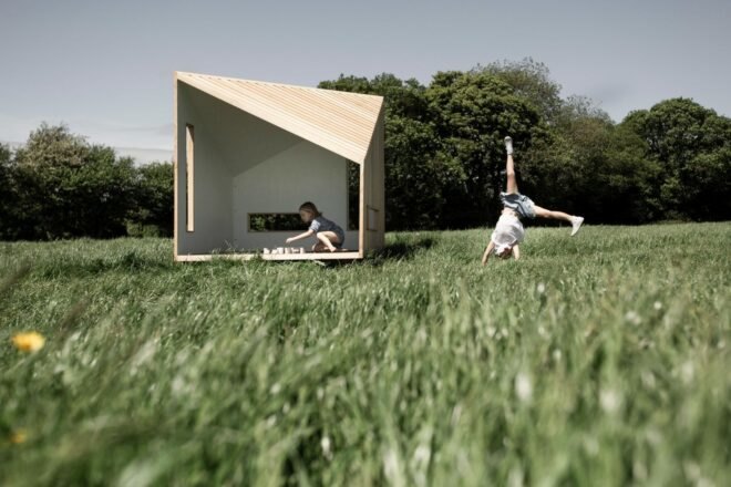 kids playing in a geometric wood cabin