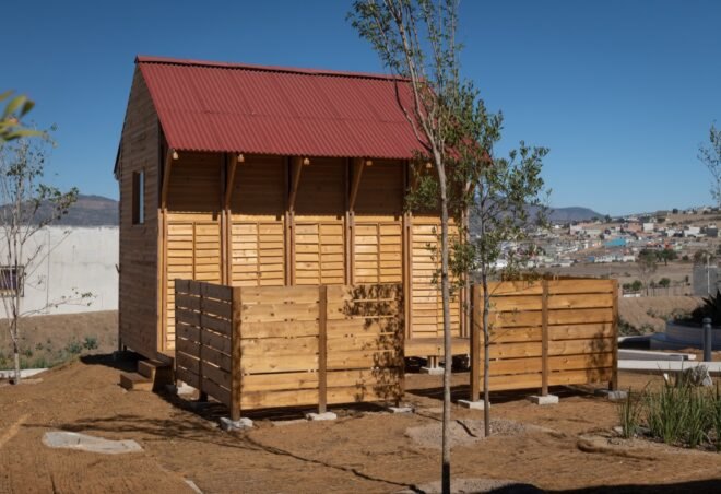 small timber home with red gabled roof and fenced-in yard