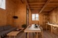 timber-lined room with small sofa, wood dining table and kitchen sink on timber table
