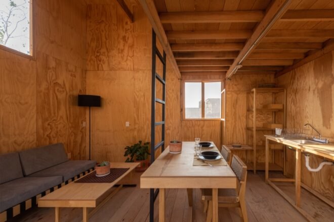 timber-lined room with small sofa, wood dining table and kitchen sink on timber table