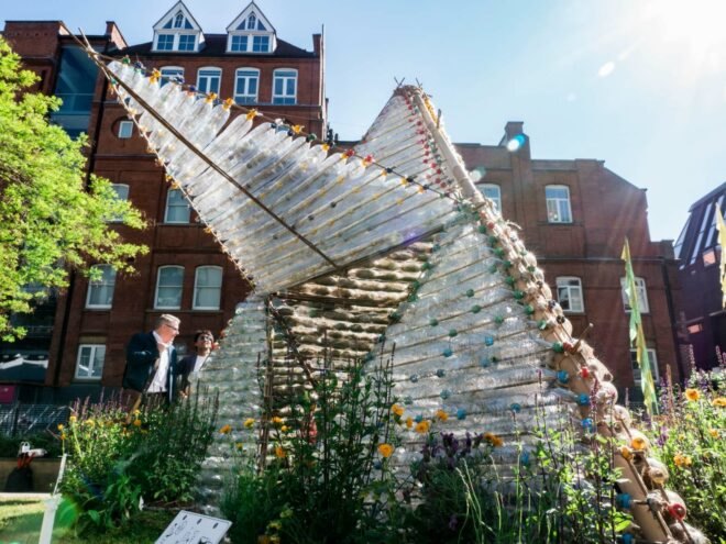 small shelter made out of recycled plastic bottles with triangular door opening upward