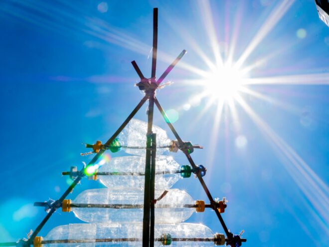 sunlight shining through top of shelter made of plastic bottles