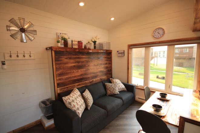 inteiror of tiny home with wooden accent wall behind a black sofa