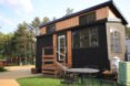 black and tan tiny home with windows and front stairwell