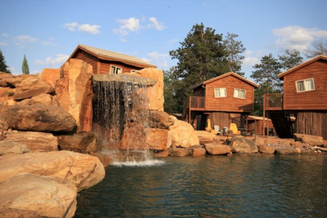 wooden cabins set around a lagoon with a waterfall