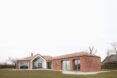 brick house with large ceiling to floor windows surrounded by grass
