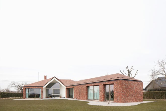 brick house with large ceiling to floor windows surrounded by grass