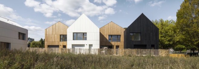 wood and straw houses surrounded by greenery with blue skies above