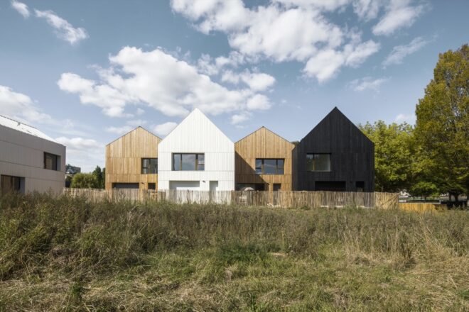 wood and straw houses surrounded by greenery with blue skies above