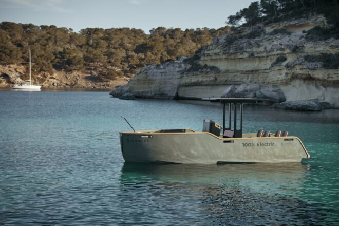electric yacht in crystal clear blue water near grassy hills