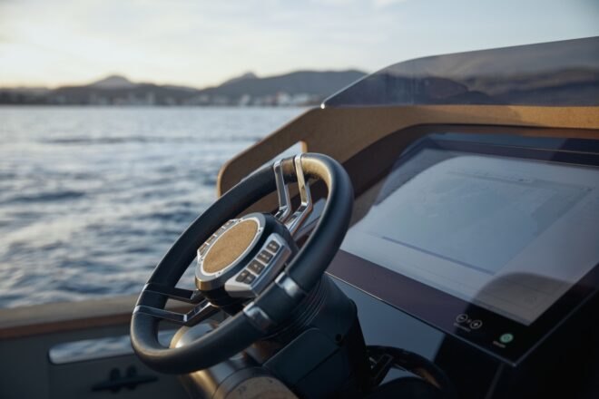 electric yacht in crystal clear blue water near grassy hills