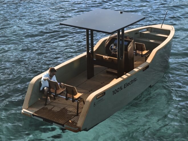 electric yacht in crystal clear blue water near grassy hills