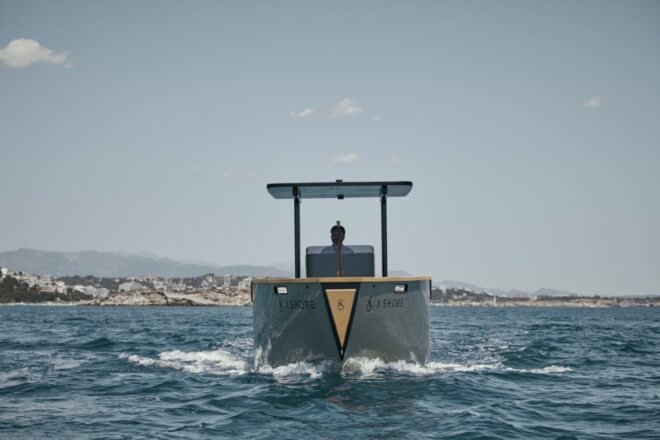 electric yacht in crystal clear blue water near grassy hills