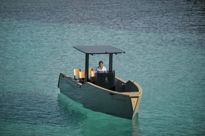 electric yacht in crystal clear blue water near grassy hills
