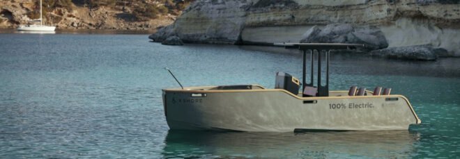 electric yacht in crystal clear blue water near grassy hills