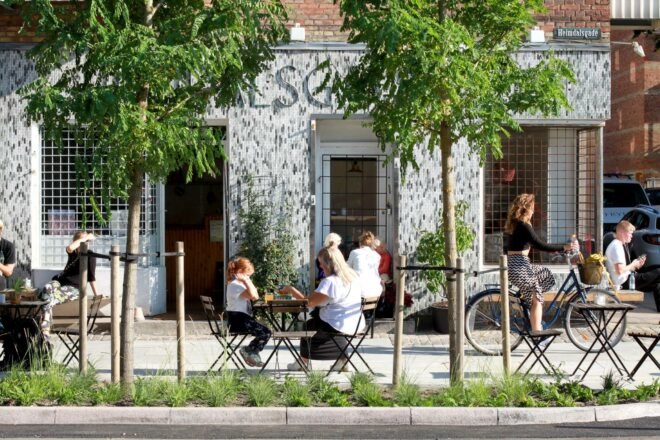 people sitting outside cafe at tables on top of rainwater-capturing sidewalk tiles