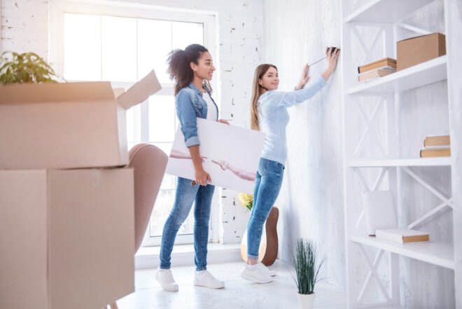 two people hanging a painting on a wall