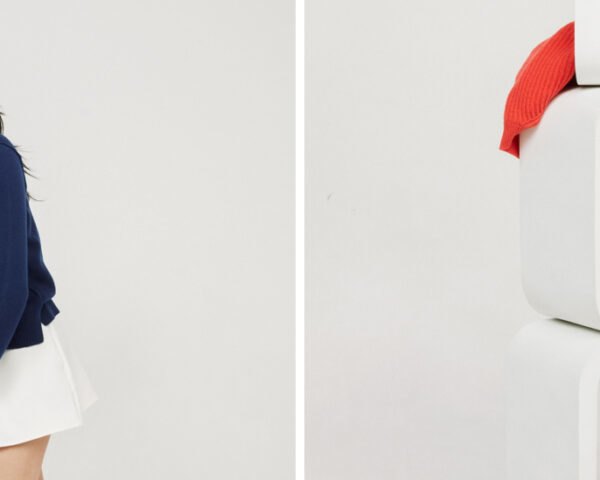On the left, girl in navy blue cashmere sweater. On the right, bright red and lavender sweaters resting on white blocks.