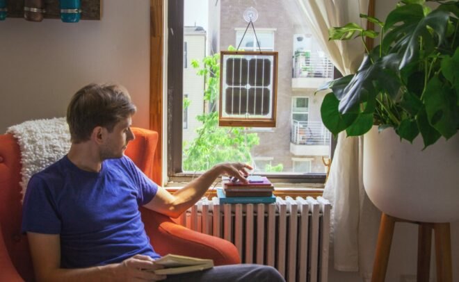 man sitting next to window with framed solar panels