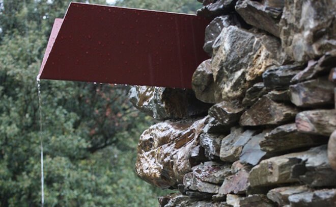 red gutter on stone building covered in rain