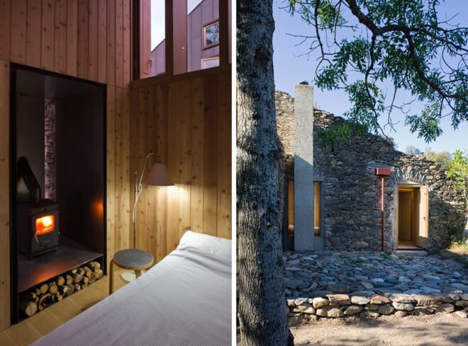 On the left, bed beside wood-burning stove. On the right, stone building near trees.