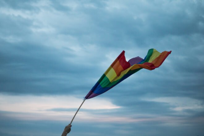 rainbow flag waving against cloudy skies