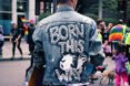 person at Pride parade wearing DIY decorated jacket that reads 