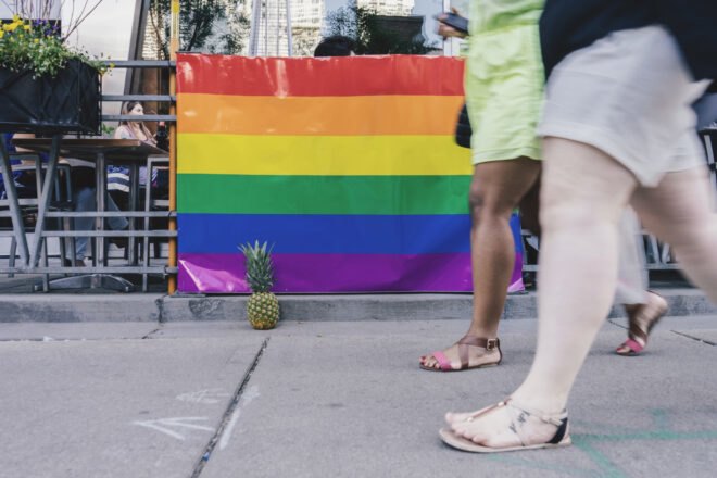 people walking by restaurant with a rainbow flag