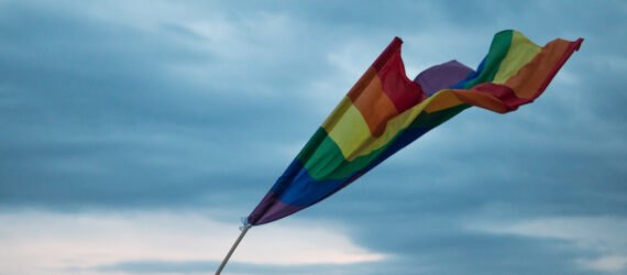 rainbow flag waving against cloudy skies