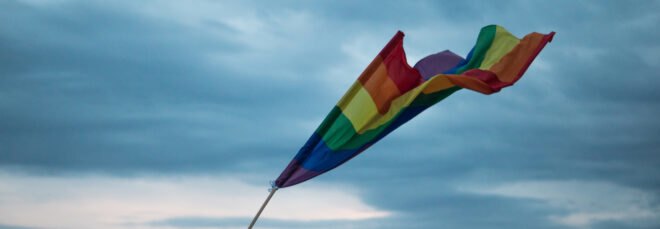 rainbow flag waving against cloudy skies