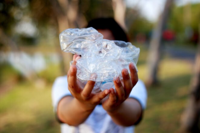 person holding a smashed plastic water bottle